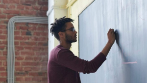 Young man writing on a chalk board