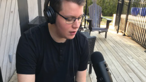 Student with headphones on recording a podcast with a microphone outdoors