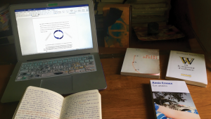 Laptop and books on a wooden desk